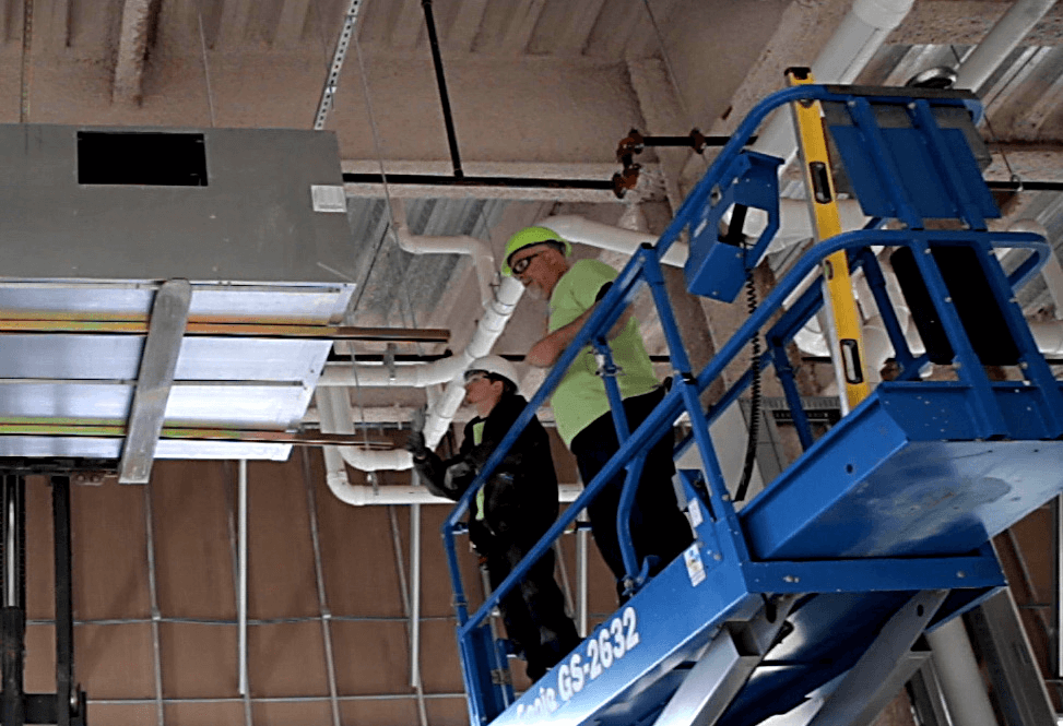 HVAC commercial installation workers on a lift