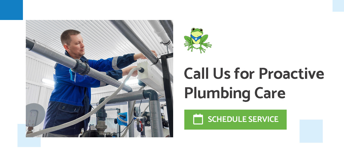 Technician in blue uniform installing or maintaining plumbing pipes in a utility room. Features GreenBox Home Services' green frog logo with text 'Call Us for Proactive Plumbing Care' and a 'Schedule Service' button.